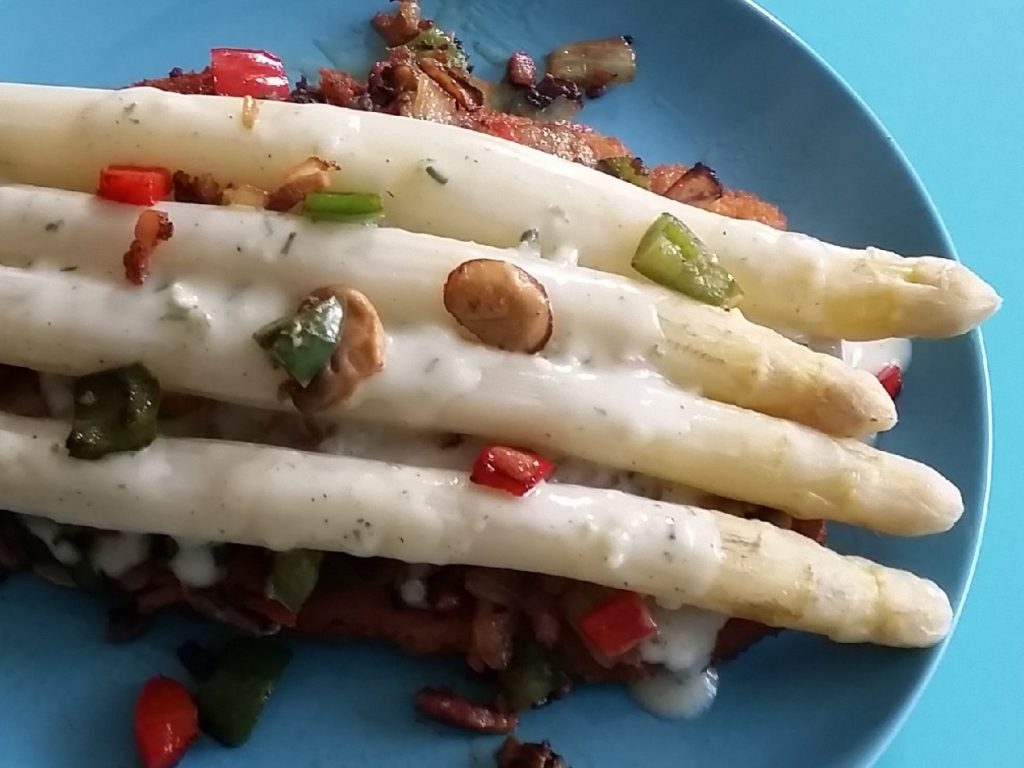 Witte asperges bovenop een boerenschnitzel met spekjes, paprika, ui en champignons