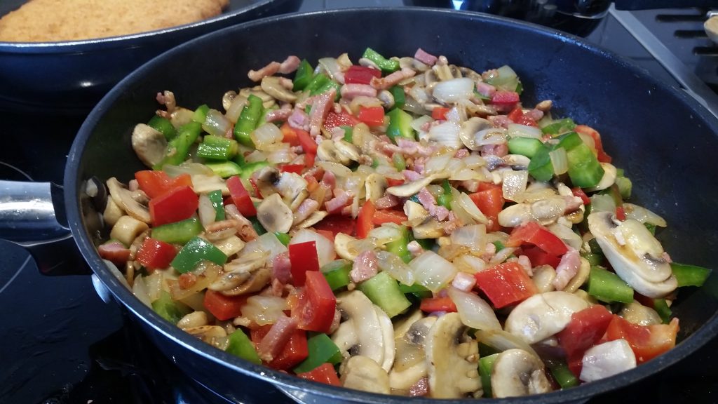 uit, champignons, paprika en spekjes in een koekenpan