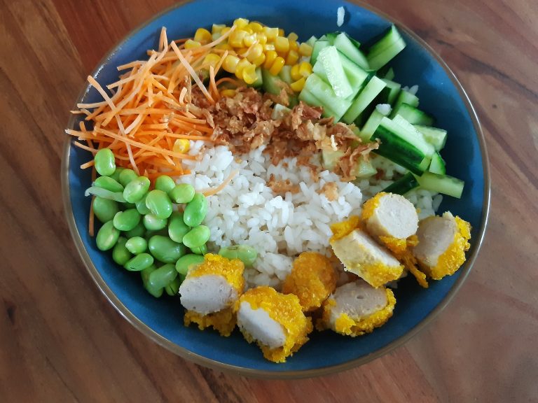 pokebowl met kip, sojabonen, wortels, komkommer en sushi rijst in een kom