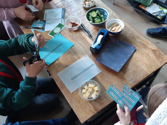 de kinderen knippen en plakken tijdens het spel Knal-Feest (van Huisarrest)